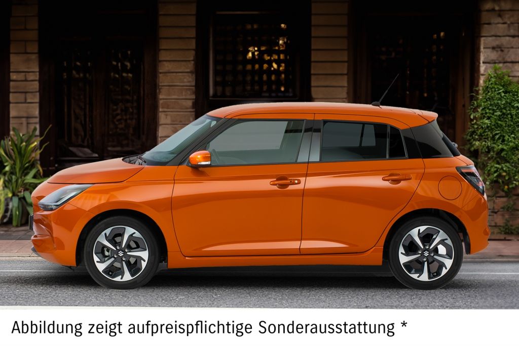 Orangener Suzuki Swift in Seitenansicht vor einer Hauswand mit Pflanzen.