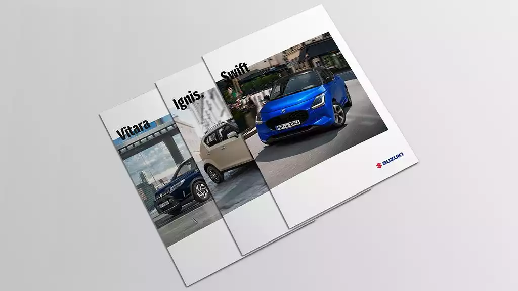 Vogelperspektive auf drei sich überlappende Kataloge des Suzuki Vitara, des Suzuki Ignis und des Suzuki Swifts