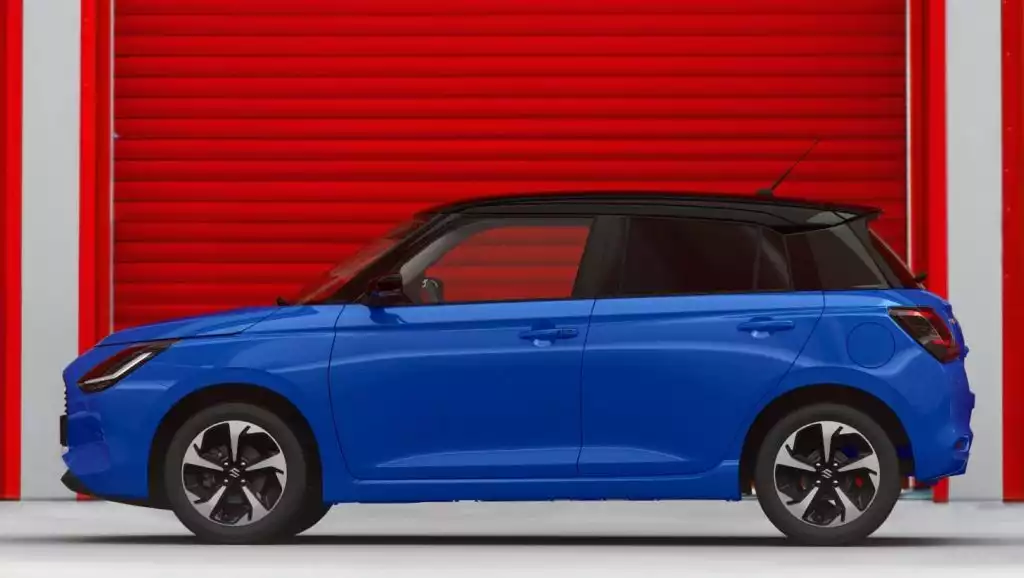 Blauer Suzuki Swift Hybrid vor rotem Garagenrolltor in Seitenansicht