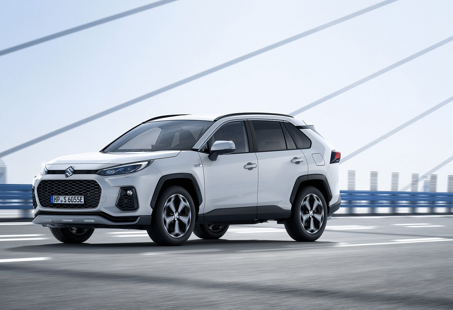 Weißer Suzuki Across PLUG-IN HYBRID Comfort+ bei Fahrt über Brücke in Front-Seitenansicht, Verbrauch 17,1 kWh/100 km, CO₂ 22 g/km, 6,6 l/100 km bei leerer Batterie