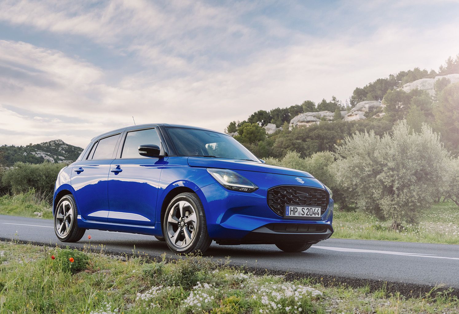 Blauer Suzuki Swift auf einer Küstenstraße in Front-Seitenansicht