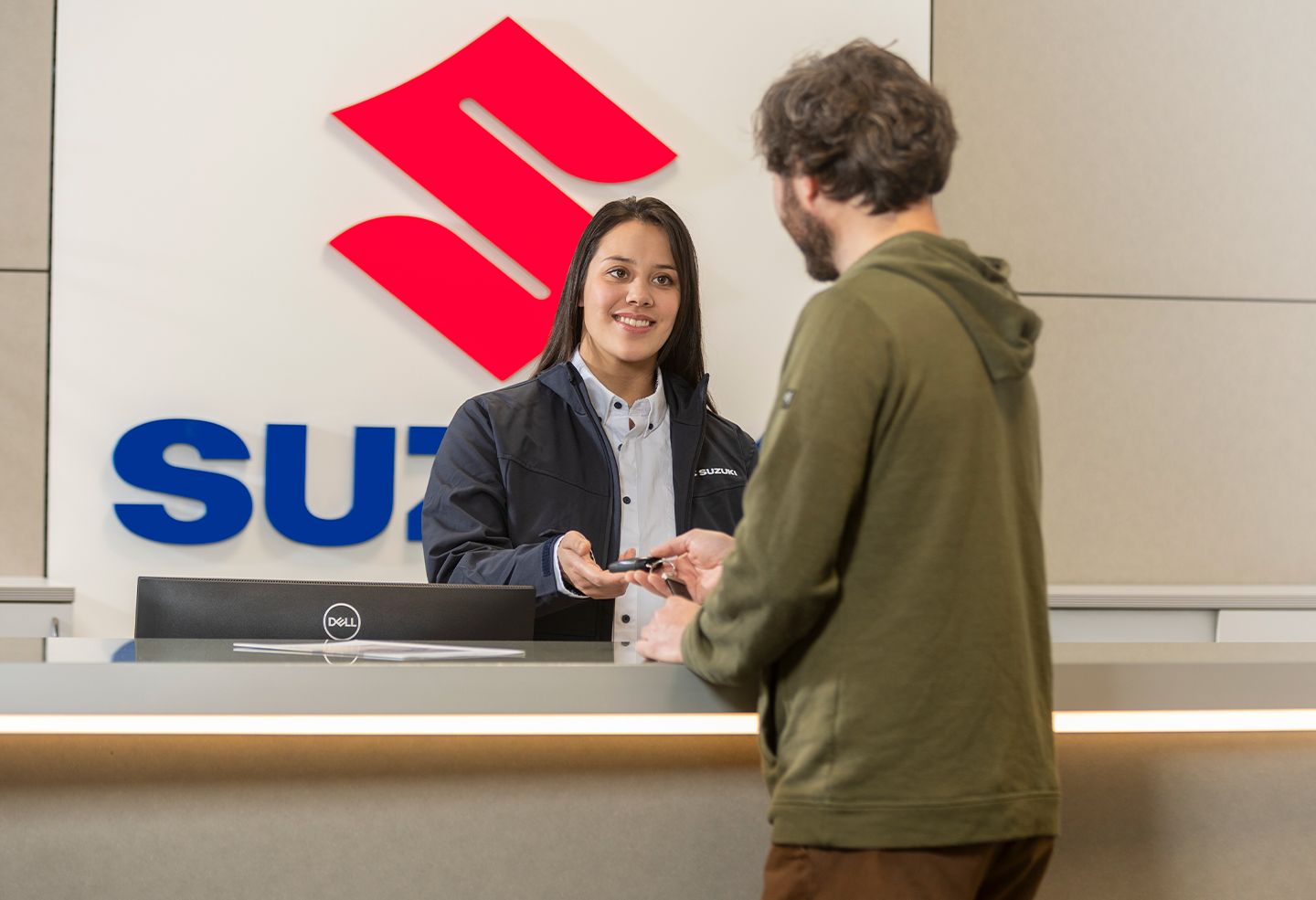 Ein Kunde übergibt seinen Autoschlüssel an eine Werkstattmitarbeiterin