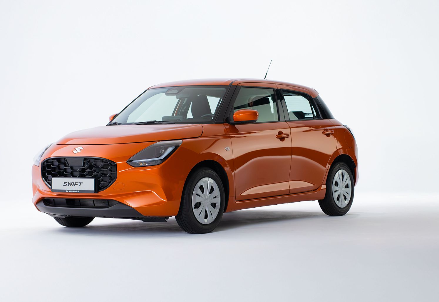 Der Suzuki Swift in orange von schräg vorne vor einem neutralen weißen Hintergrund.
