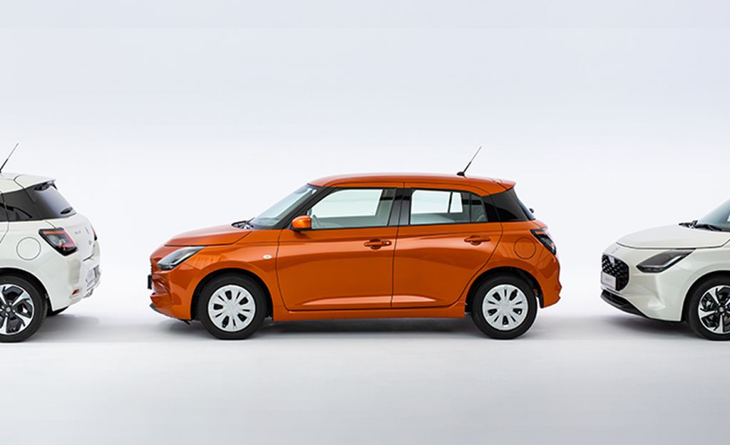 Der Suzuki Swift in orange parkt vor einem neutralen weißen Hintergrund zwischen zwei weißen Suzuki Swift.